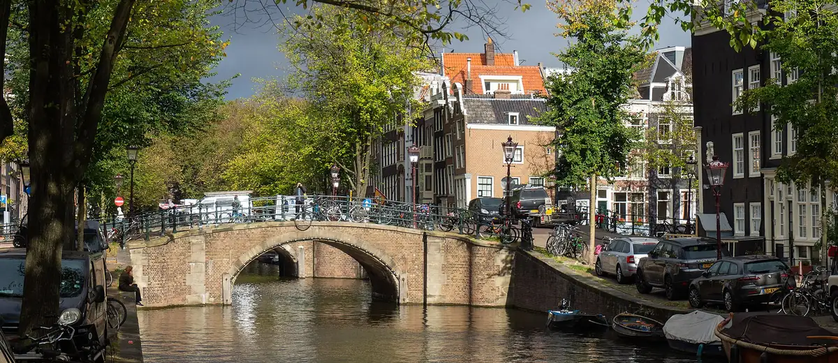 Tree-lined Reguliersgracht canal with an arched stone bridge and old gabled houses