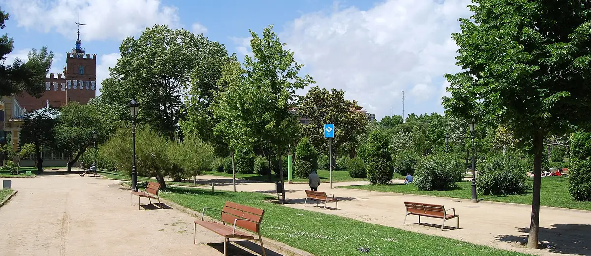 Shaded gravel path with wooden benches and trees in Barcelona's Parc de la Ciutadella