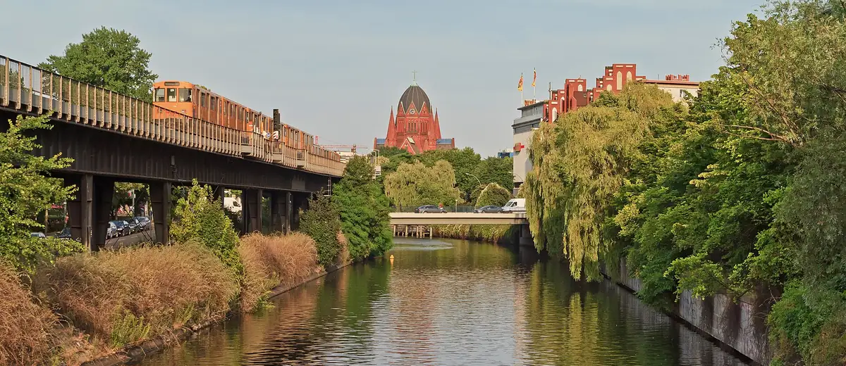 Calm Landwehrkanal in Kreuzberg with willows, an elevated railway and soft evening light