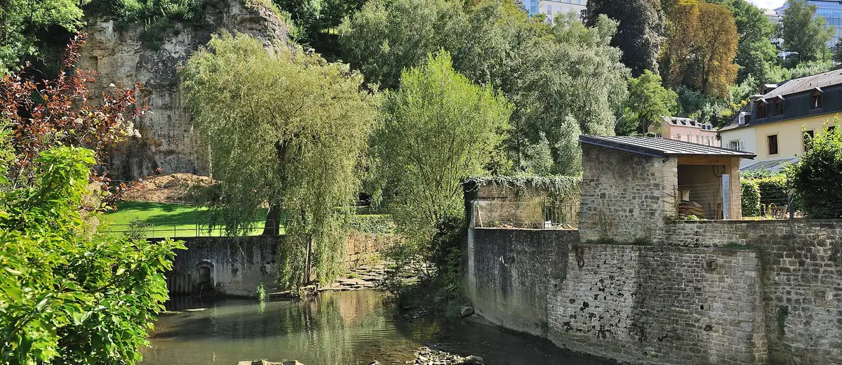 The Alzette river flows past old stone walls and willows in Luxembourg's Grund quarter
