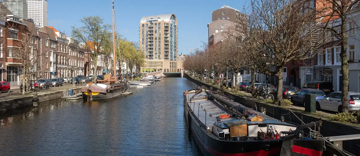 Quiet Bierkade canal in The Hague with moored houseboats under a clear blue sky